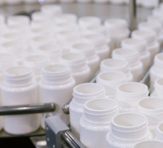 Lots of white plastic pill bottles on an assembly line.
